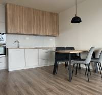 A kitchen in a 2-room apartment with a wooden decor floor and a dining table.