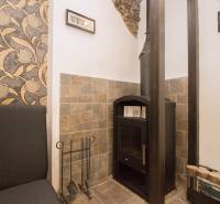 A fireplace with a stone cladding and floral wallpaper in a 2-room apartment.