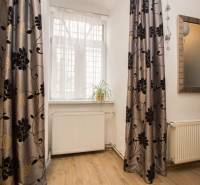 A room in a 2-room apartment with a floor featuring a wood decor, curtains, and a plant on the windowsill.