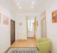 Interior of a 2-room apartment with a wooden decor floor, an armchair, and colorful paintings.