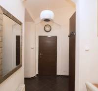 Hallway of a 2-room apartment with a coat rack, mirror, and dark doors, tiled floor.