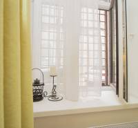 An open window in a two-room apartment with curtains and decorations on the windowsill.
