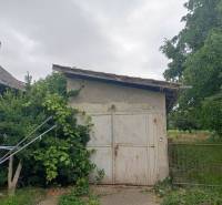 A family house in Strekov with a small shelter surrounded by greenery and trees.