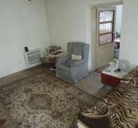 A room in a family house with a carpet, armchairs, and a bed.