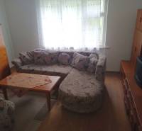 Living room in a family house with a corner sofa and a table on a floor with a wooden decor.
