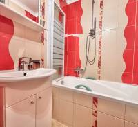A bathroom with colorful tiles and a bathtub in a 2-room apartment.