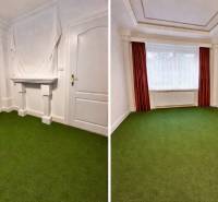 A room with white walls and a green carpet in a two-room apartment.