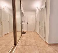 Hallway in a 2-room apartment with tiles, a mirrored wardrobe, and white doors.