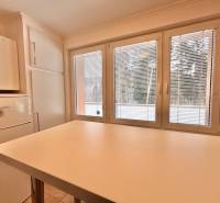 A kitchen in a 2-room apartment with a white table and a view through the window.