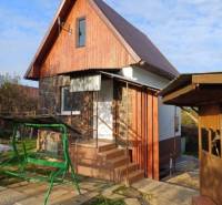 A cottage in Pozdišovce with wooden cladding and a swing in the garden.