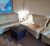 Beige sofa in the cottage with a rattan table, sunlight through the window.