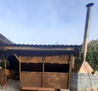 Wooden gazebo and brick chimney by the cottage in Pozdišovce.