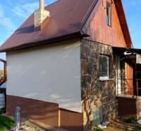A cottage in Pozdišovce with a stone facade and a brown metal roof.