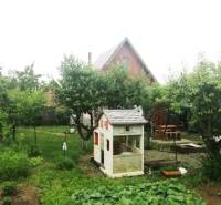 The garden in Pozdišovce with a children's playhouse and fruit trees near the cottage.