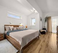 Bedroom in a family house with a bed, decorative elements, and a floor with a wood design.