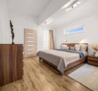 Bedroom with wood-patterned flooring, a bed, and a dresser in a family house.
