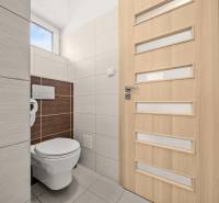 A toilet in a family house with light tiles and doors with vertical stripes.