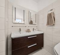 A bathroom in a family house with a double sink and a dark cabinet.