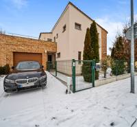 A family house in Konopiská in Bratislava-Čunovo with a brick facade, a snow-covered walkway, and a car.
