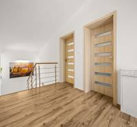 A hallway in a family house with a wooden decor floor, minimalist railing, and an art photograph.