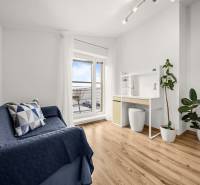 A room in a family house with a wooden decor floor, a blue sofa, and a desk.