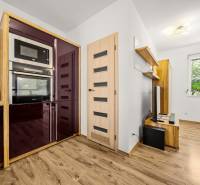 A kitchen in a family house with a wood-patterned floor, modern appliances, and floating shelves.