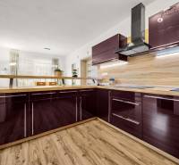 A kitchen in a family house with a wooden decor floor and a glossy kitchen unit.