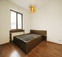 Bedroom in a two-room apartment with a solid wood bed and a floor with a wooden decor.