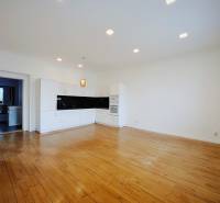 A kitchen in a 2-room apartment with white cabinets and a wood-patterned floor.