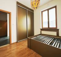 A bedroom in a two-room apartment with a wood-patterned floor, a large wardrobe, and a radiator.