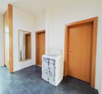 A hallway in a 2-room apartment with a dark floor and wooden doors.