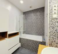 A bathroom in a 2-room apartment with a bathtub, mosaic tiles, and storage spaces.