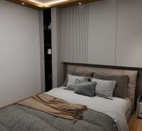 Bedroom with a bed, built-in lighting, and wooden decor flooring in a 3-room apartment.