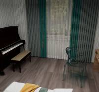 Piano, table with a chair, and floor with wooden decor in a 3-room apartment.