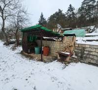 Winter scene in Lieskovec, Dubnica nad Váhom with a cottage, shelter, and brick grill.