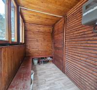 Wooden porch of the cottage with a wood-patterned floor and a storage bench.