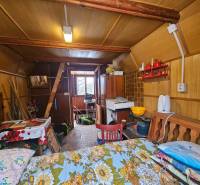 Interior of a cabin with wooden decor, furniture, and kitchen utensils.