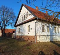 A family house in Orávka with a large garden and a nearby tree in the winter season.