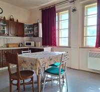 A kitchen in a family house with wooden furniture and burgundy curtains.