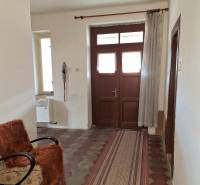 The hallway of a family house with a tiled floor, an armchair, and a curtain.