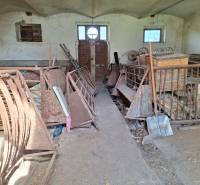 An old barn in a family house with rusty metal equipment and wood on the floor.
