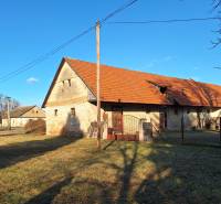 A stone family house in Orávka with a red roof surrounded by a grassy plot.