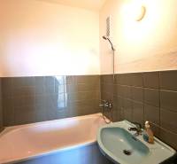 A bathroom with green tiles, a bathtub, and a sink in a 4-room apartment.