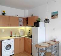 Kitchen corner in a holiday apartment with a washing machine, refrigerator, and table.