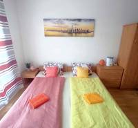 A bedroom in a holiday apartment with two beds, a painting, and colorful bedding.