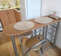 Kitchen corner of the holiday apartment with a bar table, stools, and a floor with a wooden decor.