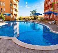 A holiday apartment in Burgas with a swimming pool, sun loungers, and umbrellas on a paved terrace.