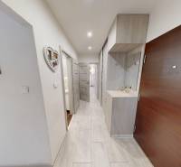 A hallway in a 2-room apartment with a coat rack and white walls.