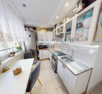 A kitchen in a 2-room apartment with a wooden decor floor, bright lighting, and modern equipment.