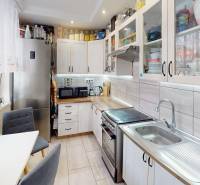 A kitchen in a 2-room apartment with white cabinets and silver appliances.